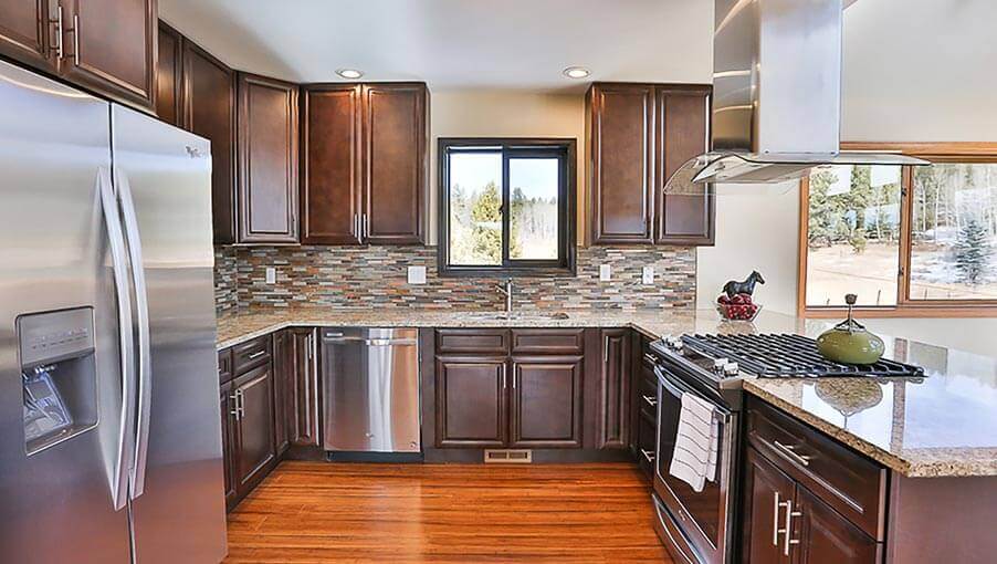 L-shaped kitchen with dark brown wood cabinets and granite countertops.