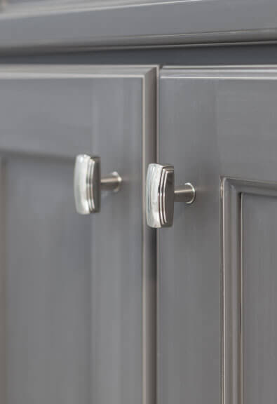 Brushed nickel knobs on gray recessed panel cabinets.