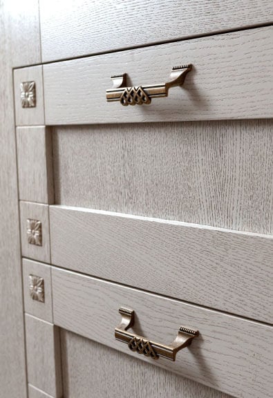 Embellished metal handles on ash wood cabinets.
