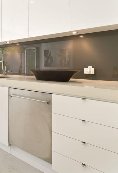 White slab cabinets in contemporary kitchen with black floors and long island.