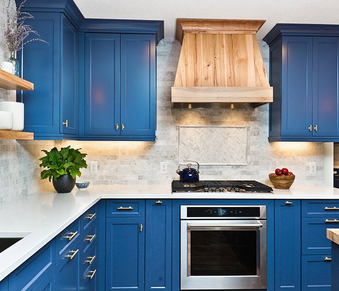 Blue kitchen with wooden open shelving and reclaimed wood hood range cover.