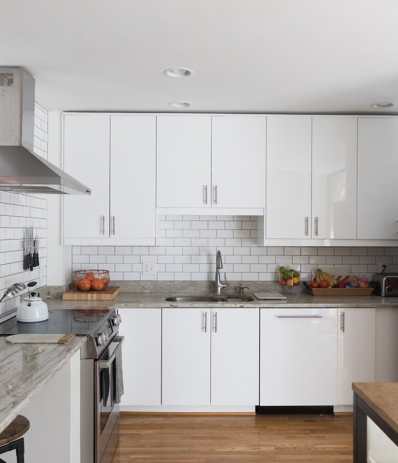 Glossy white slab kitchen cabinets in a small modern space.