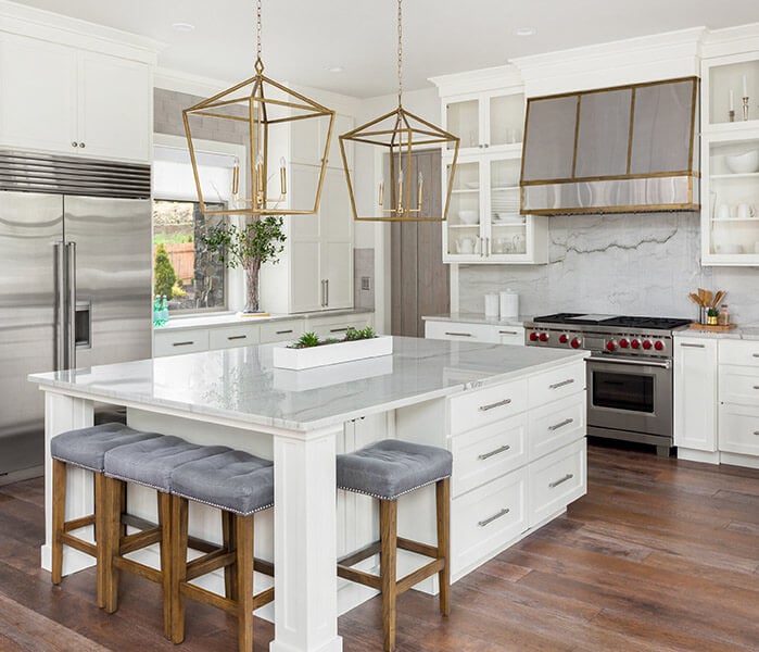 Large kitchen with white shaker cabinets, oversized island and glass-front upper cabinets.