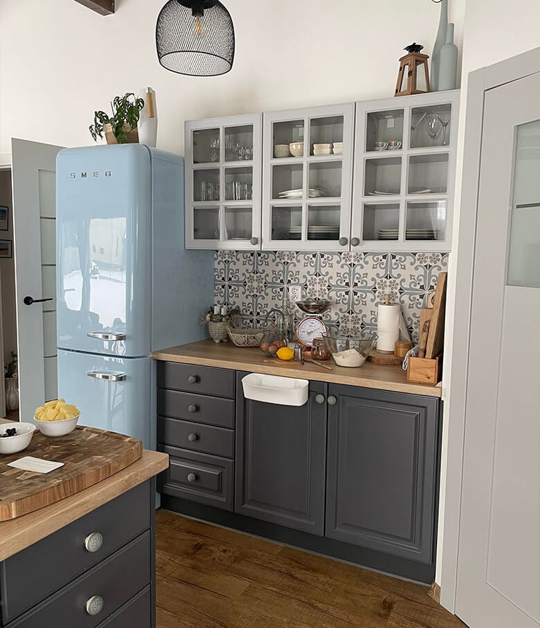 Small kitchen wie nostalgic vibes, dark base cabinets and white glass-front wall cabinets.