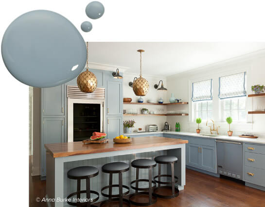 Kitchen with blue-gray painted cabinets and island with black metal stools.
