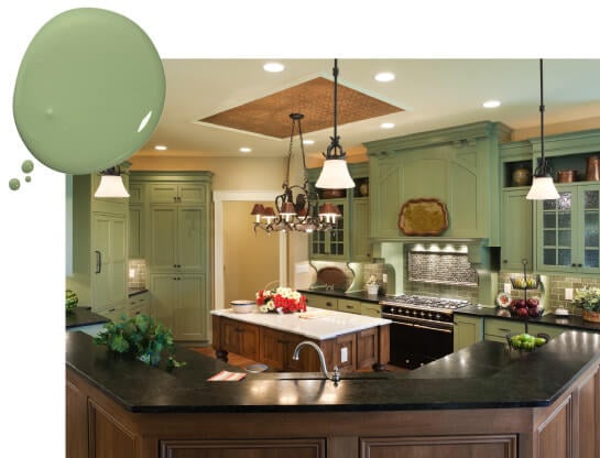 Tuscan kitchen with black granite countertops, painted green cabinets, abd wrought iron chandelier and pendant lights.