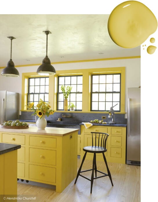 Kitchen with yellow cabinets, gray countertops and sunflowers on kitchen island.