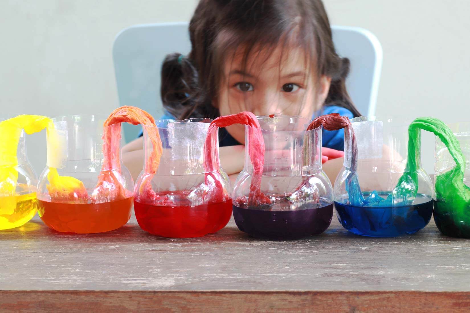 Little girl admiring her rainbow colored science experiment.