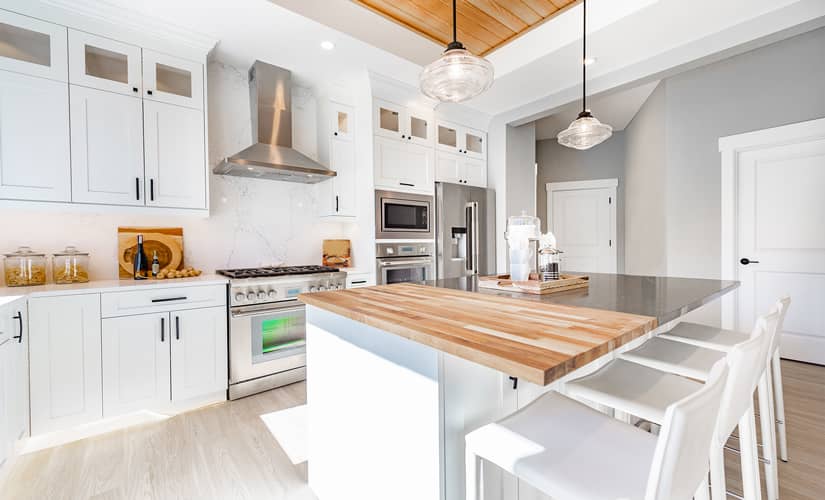 A white kitchen with a stone and butcher block countertop - a kitchen design trend for 2023