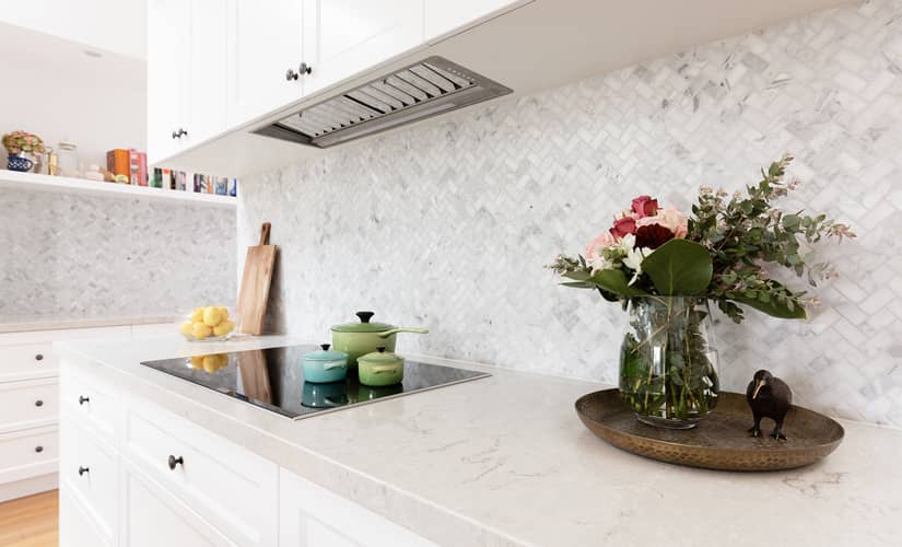 A white kitchen with a herringbone-patterned backsplash and trendy kitchen decor
