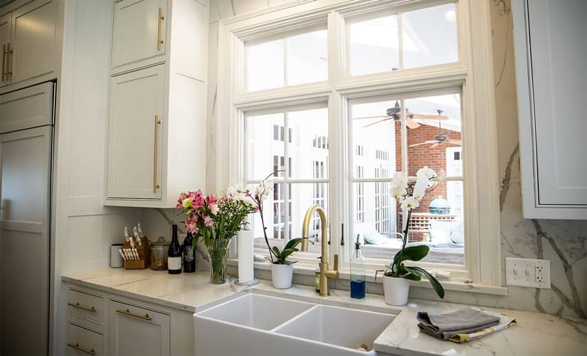 A white kitchen with brass hardware overlooking a sunroom