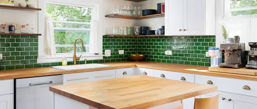 A kitchen design with green tile backsplash and butcher block counter