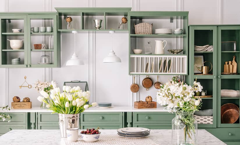 A white kitchen has green cabinets, a top kitchen design trend for 2023