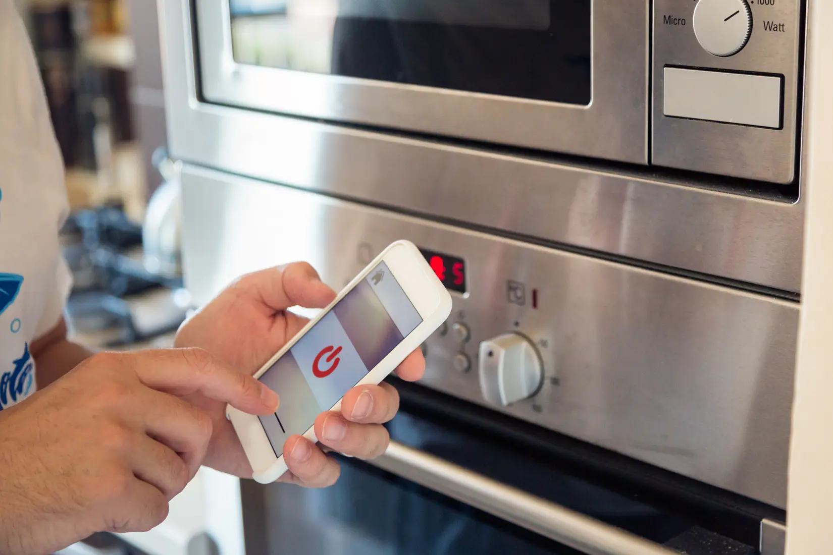 Someone turning their smart oven on with a smartphone.