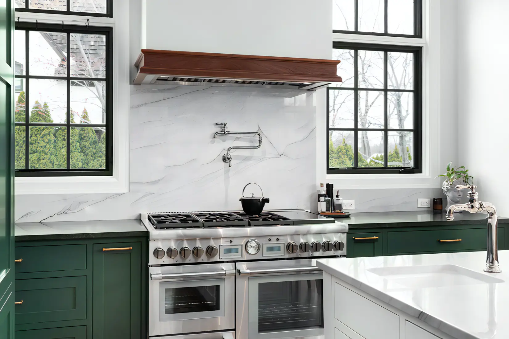 A green and white two-toned kitchen with quartz countertops.