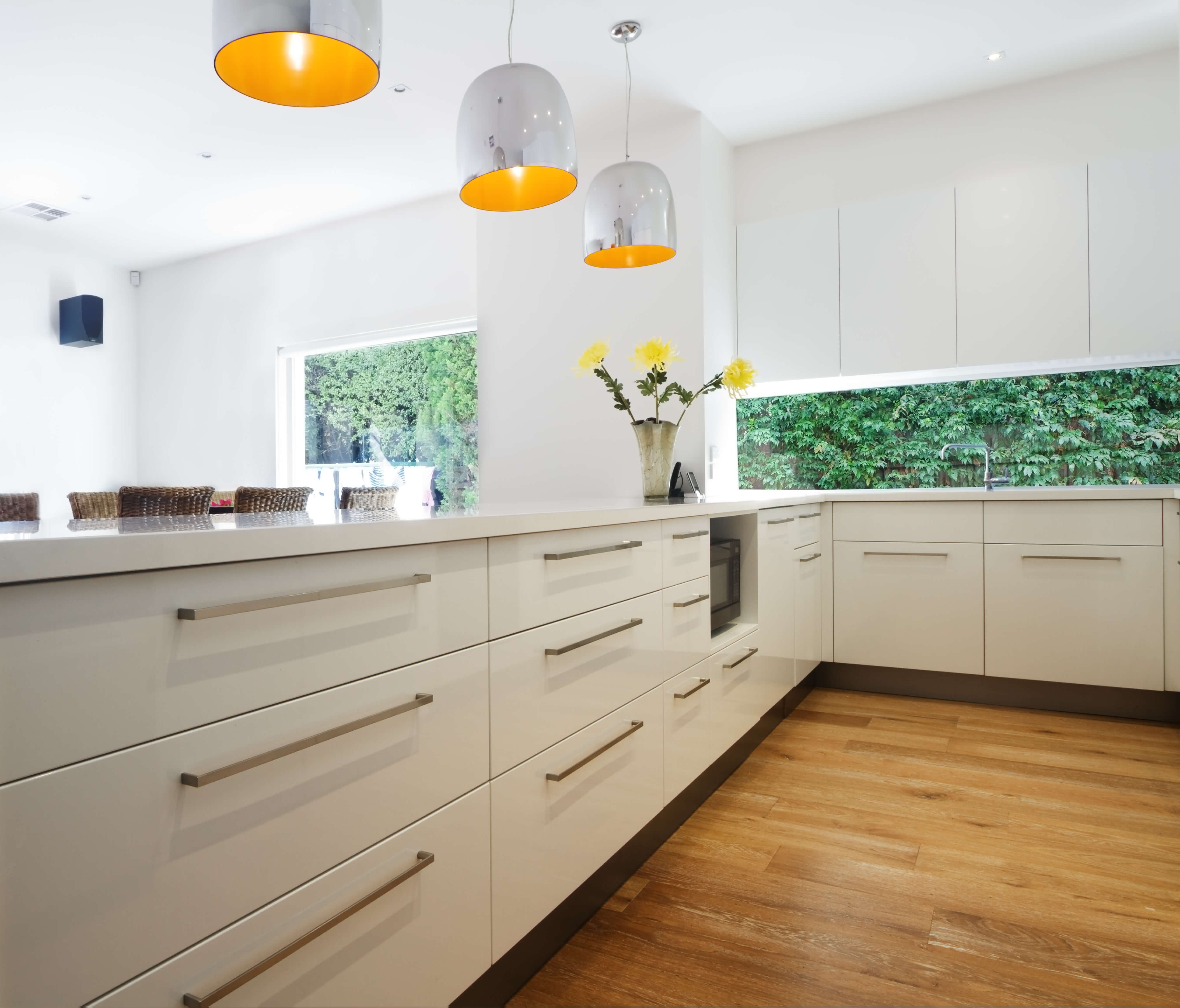 A light kitchen with glazed shining white cabiets and stainless steel accents.