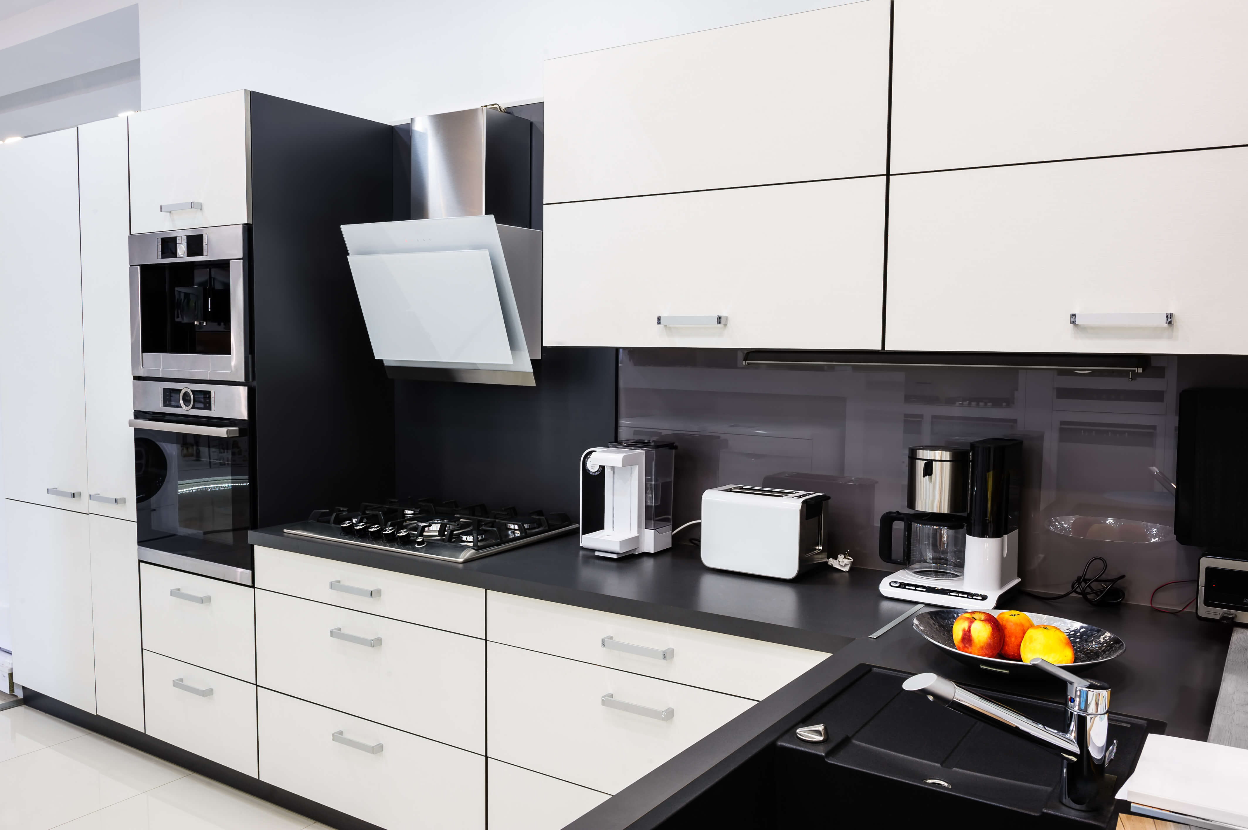 A modern kitchen with white cabinetry and black counter tops.