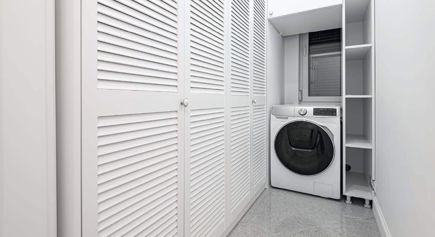 Narrow laundry room with white floor-to-ceiling storage closets.