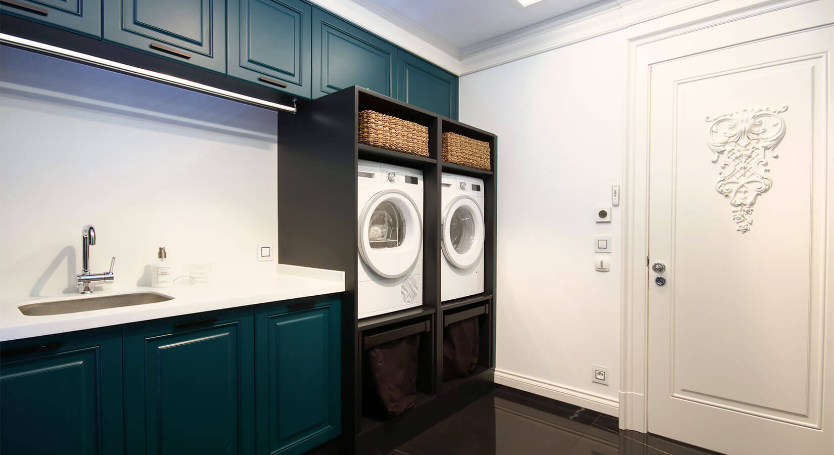 Laundry room with dark teal cabinets, black open cabinets, and white countertop.