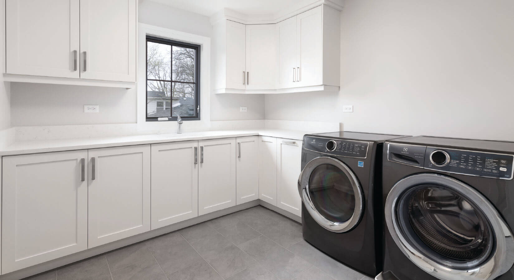 Laundry room with large white cabinets and dark gray appliances.