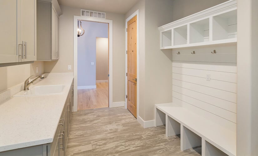 Laundry room with white bench and cubbies.