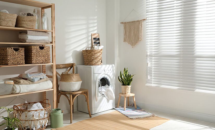 Large wood free standing shlf unit in laundry room with wicker baskets and towels.