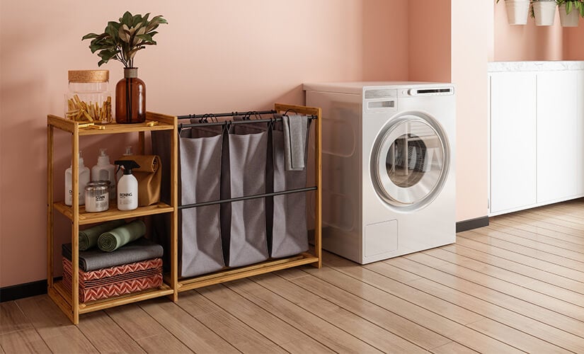 Free-standing laundry room shelf unit with three hampers next to white washing machine.