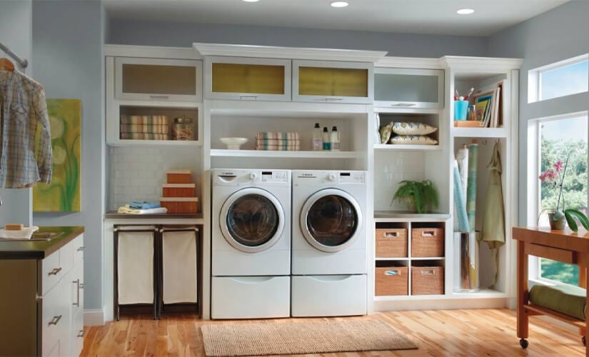 Laundry room with white washer and dryer, open cabinets, and frosted class cabinets on top.
