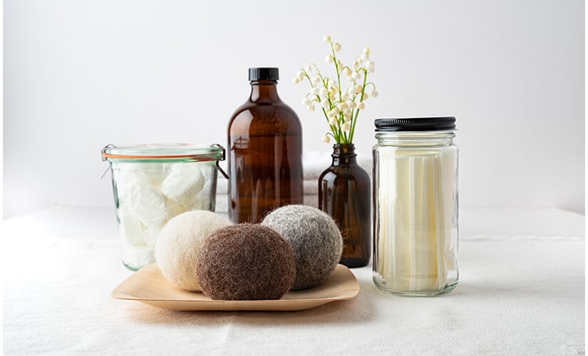 Glass jars filled with detergent and dryer sheets next to dryer balls.