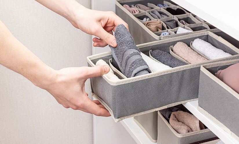 Man organizing hand towels in drawer divider.