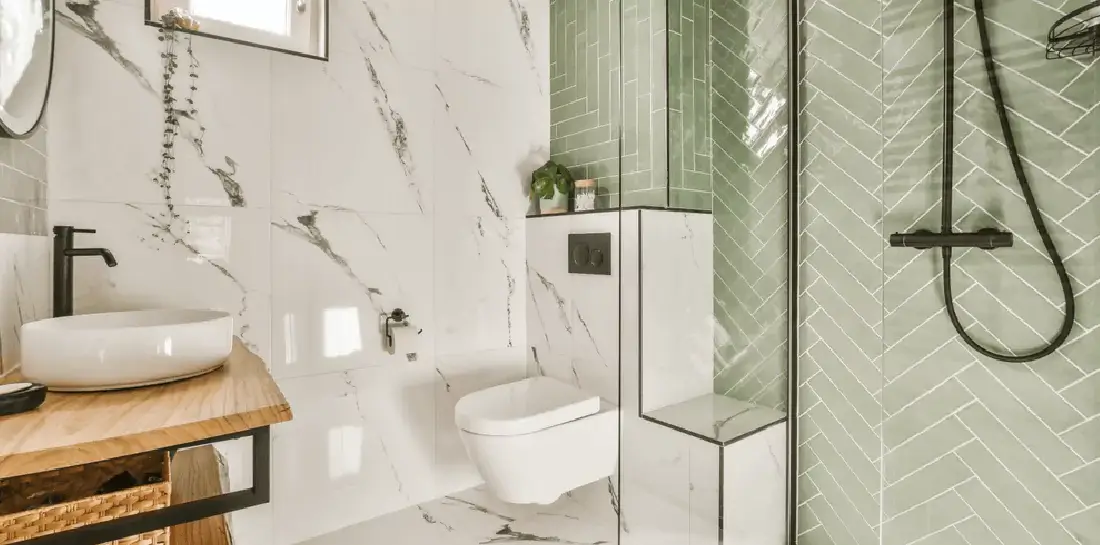 Bathroom with white marble and light green herringbone tiles.