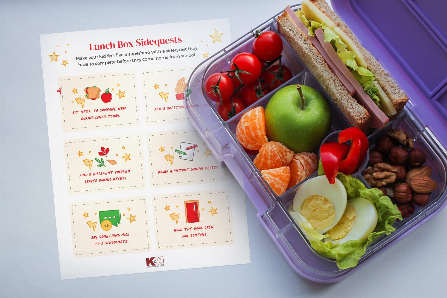 Printable lunch box sidequests next to a blue lunch box filled with eggs, fruits, veggies, nuts, and a sandwich.