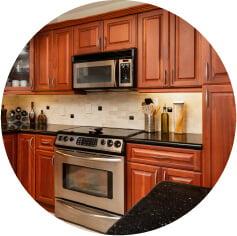 Brown maple wood kitchen cabinets with black countertops.