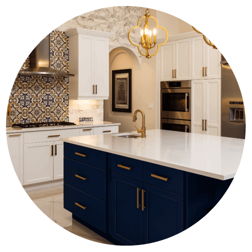 Glamorous kitchen with white and dark blue two-toned cabinets, brass hardware and eccentric tile backsplash.