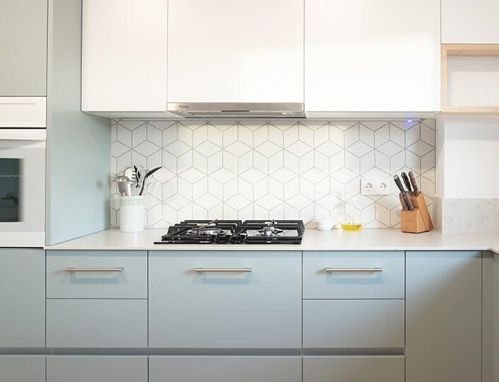 Bright, modern kitchen with light blue MDF cabinets and white backsplash tile.