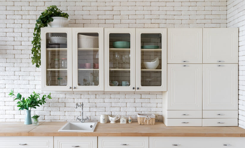 Kitchen with white brick backsplash and cream wall cabinets.