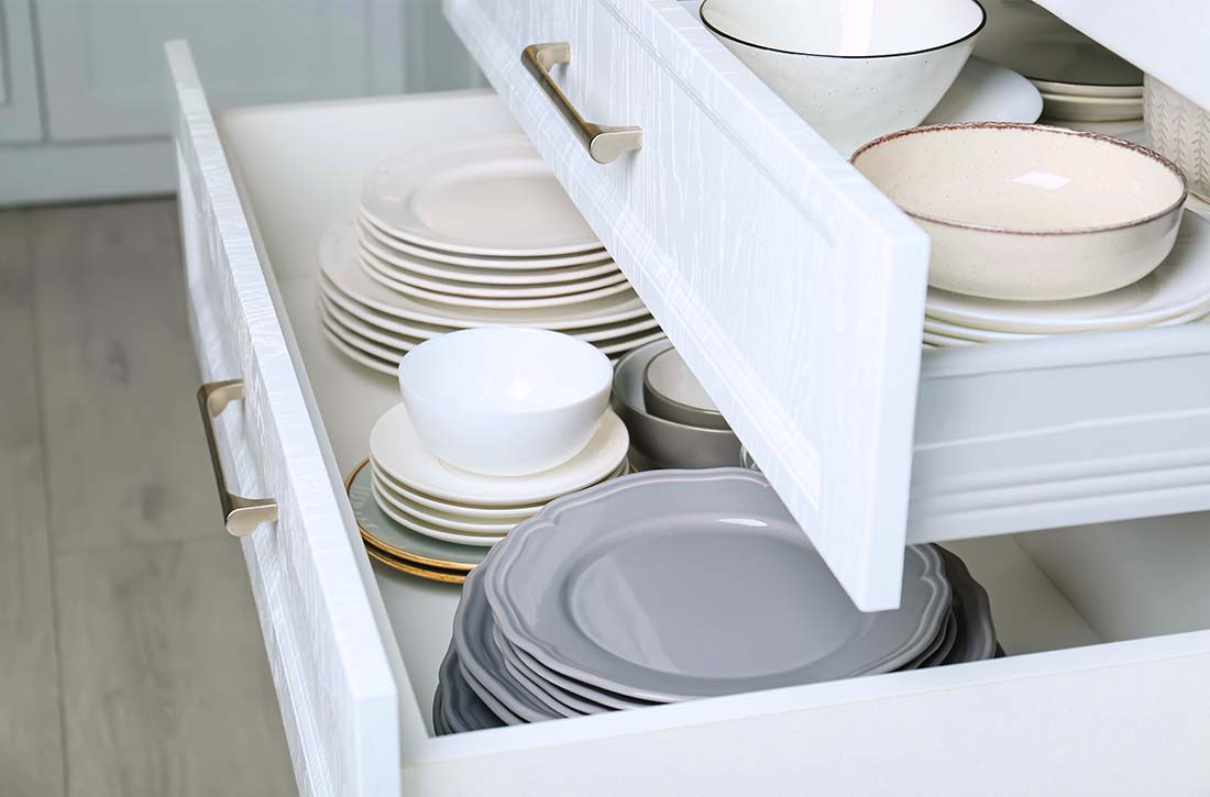 Neutral dishware sitting in kitchen drawers.