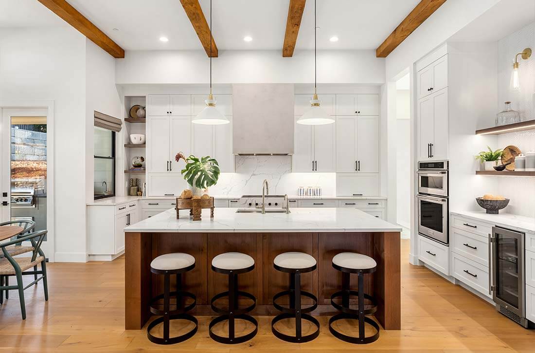 Extra large island in white kitchen with natural wood accents.