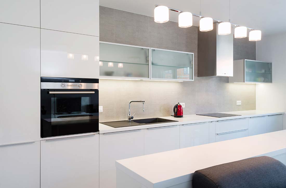 Glass upper cabinets in a white minimalist kitchen.