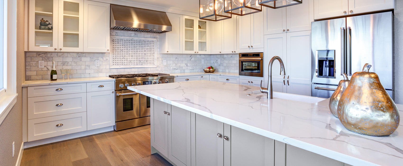bright modern kitchen with white shaker cabinets, stainless steel appliances and gray marble subway tile backsplash