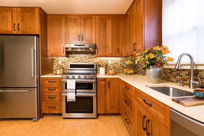 Transitional kitchen with natural wood kitchen cabinets, beige countertop, and brown mosaic tile backsplash.
