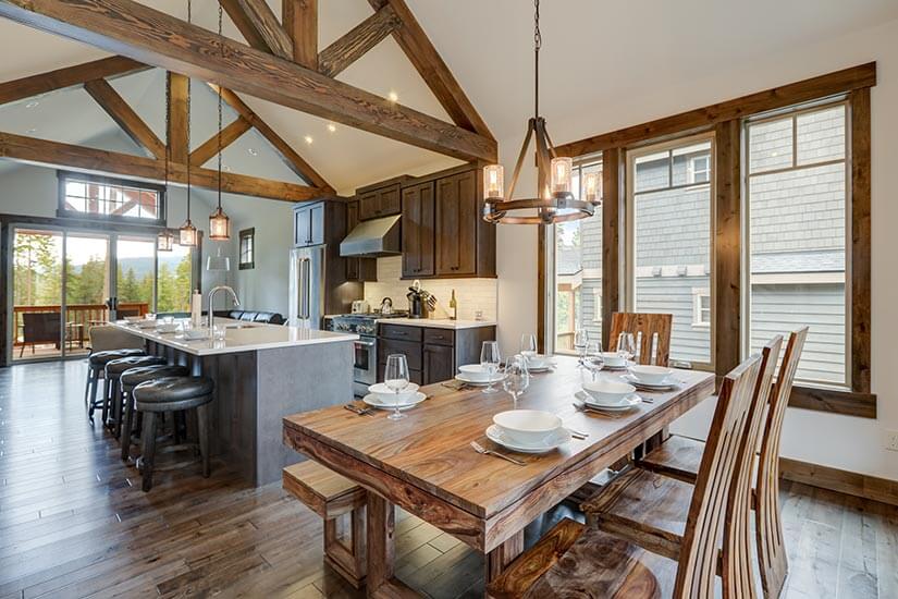 Farmhouse kitchen with wood rafters, dark wood cabinets, a large kitchen island, and a rustic dining table.