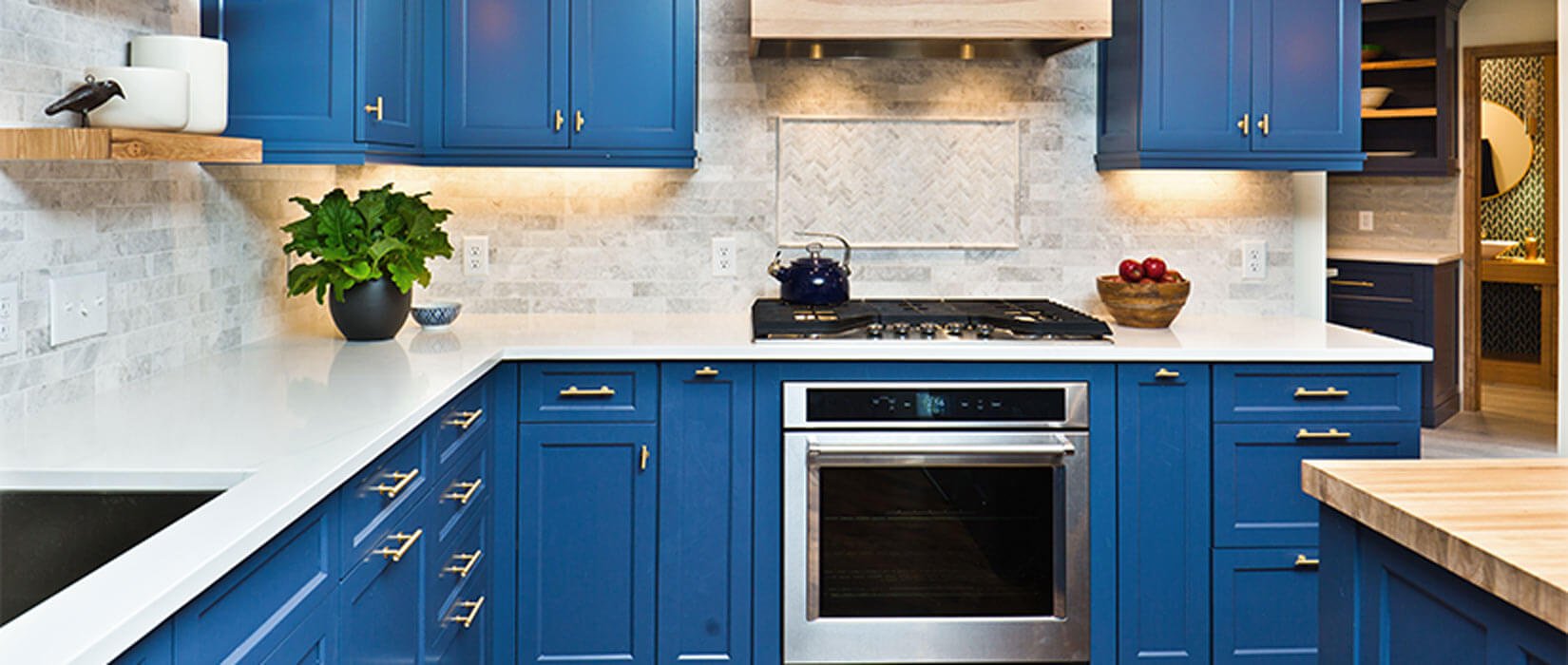 Kitchen with white countertops and dark blue cabinets with gold handles and pulls.