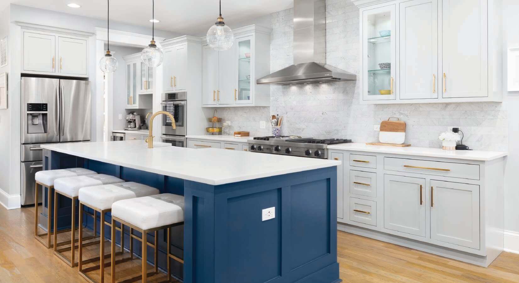 Kitchen with white cabinets and navy blue kitchen island with white countertops and gold hardware.