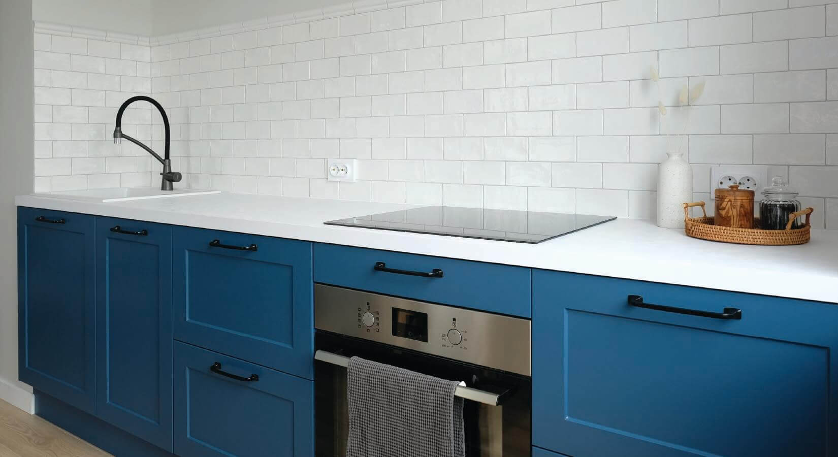 Kitchen with dark blue shaker cabinets, white countertop, and white tile backsplash.