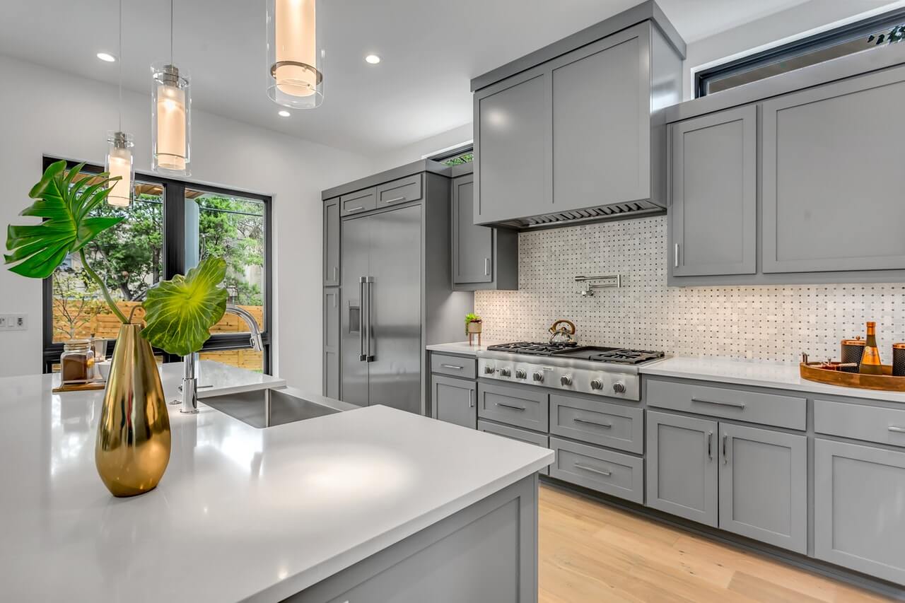 A modern one-wall kitchen with light gray cabinetry and white countertops.