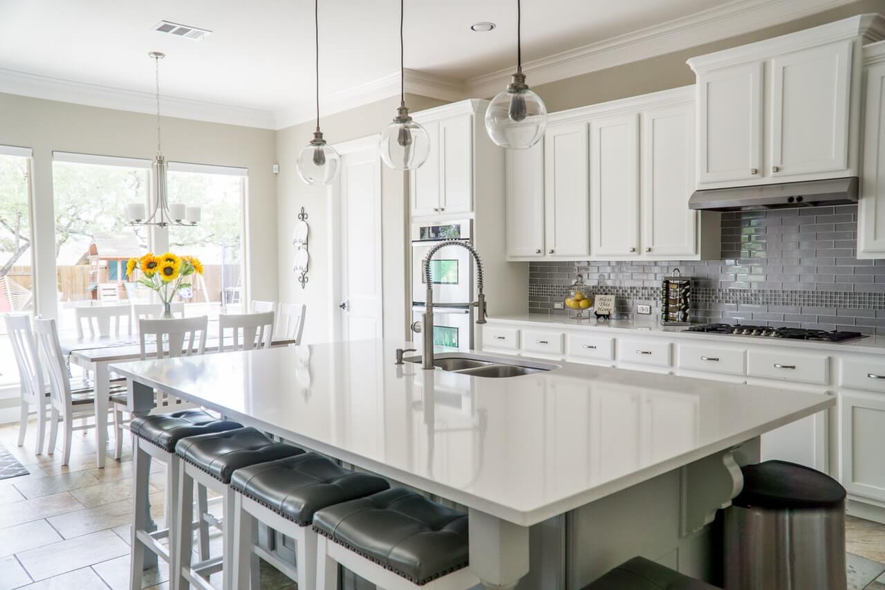 A bright one-wall kitchen with white cabinets and white countertops.