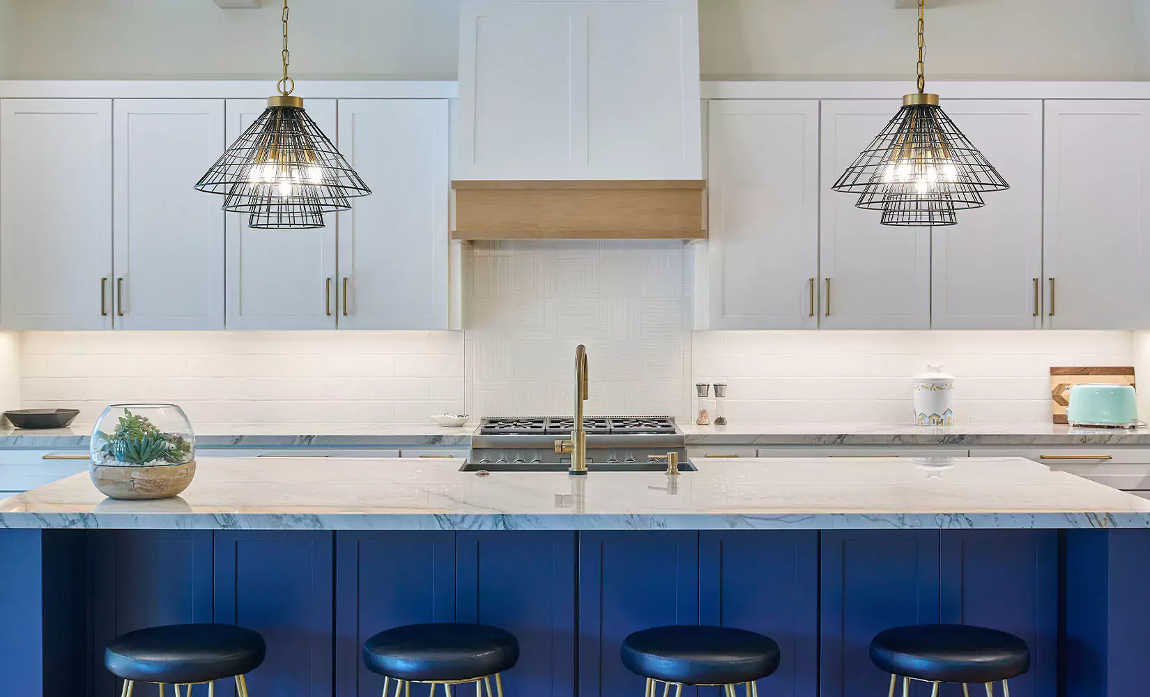 One-wall farmhouse kitchen with statement cage pendant lights over kitchen island.