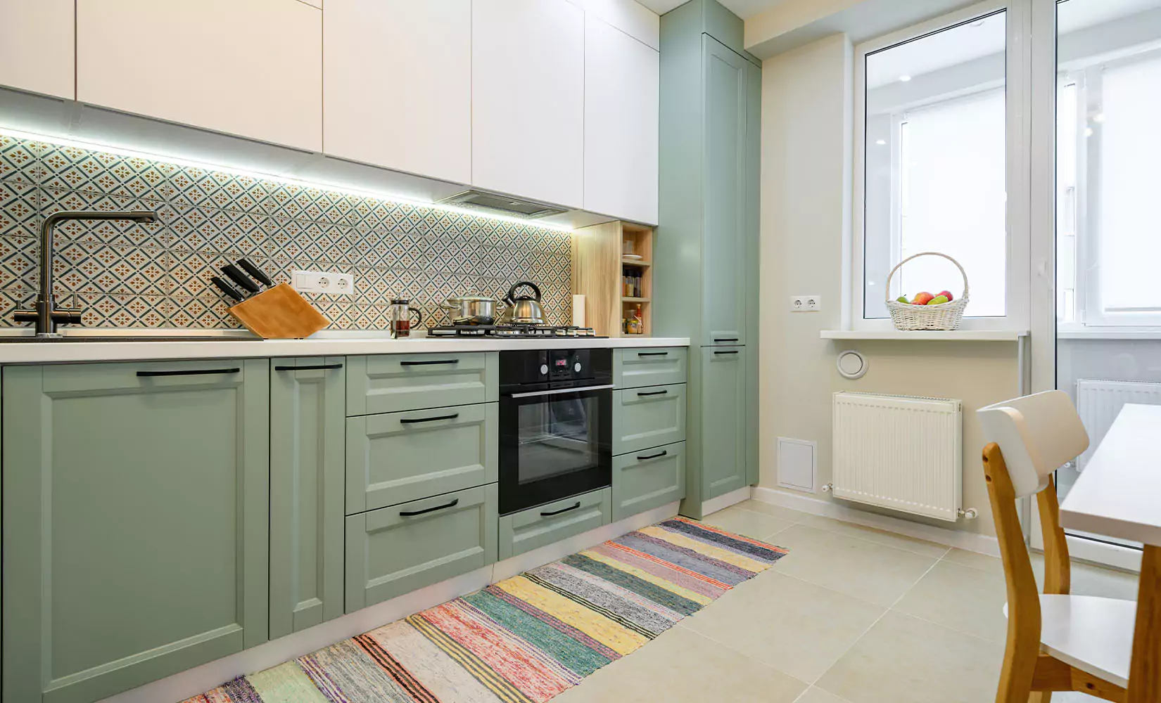 One-wall kitchen with green cabinets and colorful tile backsplash.