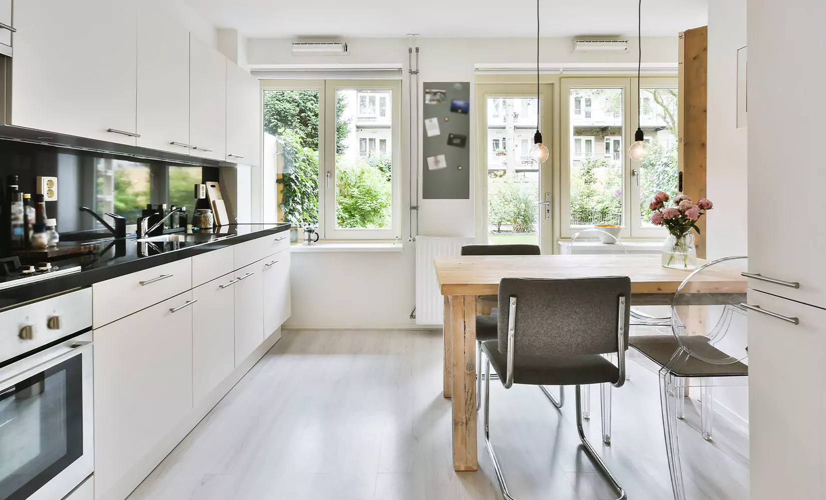 One-wall kitchen with stainless steel cabinet hardware and dining chairs.